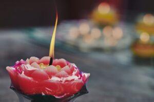 A burning candle shaped like a rose bloom.